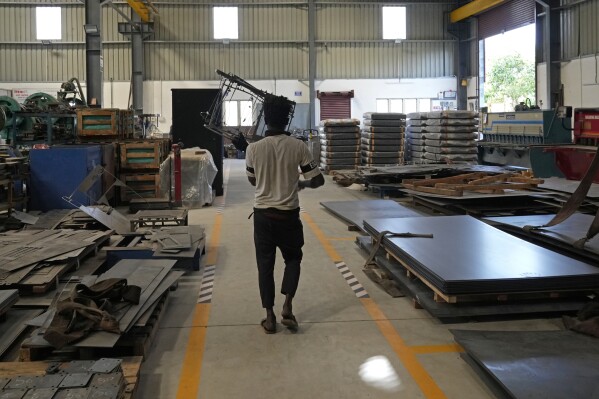 A worker carries steel waste at a factory in a suburb of Bengaluru, India, Thursday, Feb. 27, 2025. (AP Photo/Aijaz Rahi)